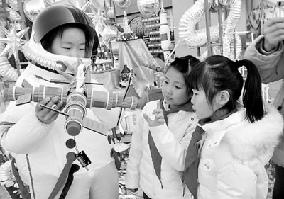 身穿航天服的学生手持天宫空间站模型吸引同学前来观看